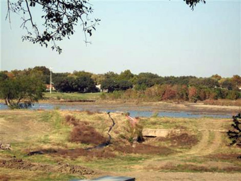 During Dredging - A view of the lake from the south, looking over the long earthen dam. The lake had been drained as part of the dredging operations, but it is partially filled with collected rain water in this picture.
